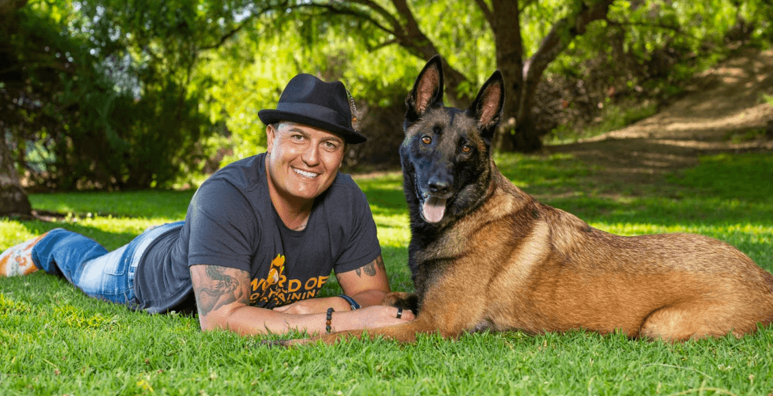 Ryan from World of Dog Training relaxing in the grass with his Belgian Malinois
